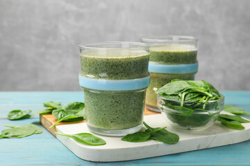 Tasty spinach smoothie and ingredients on light blue wooden table, closeup