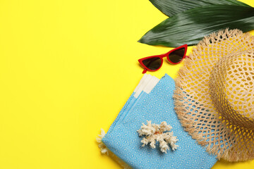 Flat lay composition with beach towel and other summer accessories on yellow background. Space for...