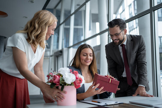 Business team giving gifts and flowers to colleague in office