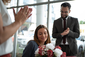 Business team celebrating success with flowers and applause in the office