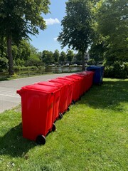 Many color trash bins on green grass in park