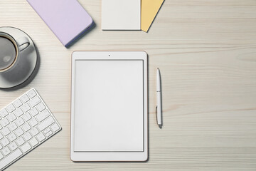 Tablet, different stationery, coffee and computer keyboard on light wooden table, flat lay. Space...