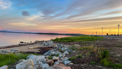  Panoramic view of still lake with cloudy sky and fading daylight. Serene horizon with soft colors creates a mood of calm and quiet.
