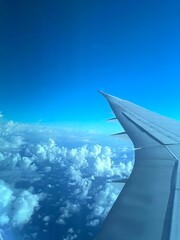 plane wing flying over clouds in a blue sky