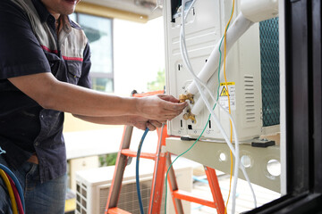 HVAC Technician Connecting Pipes to Outdoor AC Unit, Professional Installing or Repairing an Air...