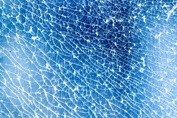 Abstract texture of a shattered blue surface. Intricate cracks form a network, highlighted by...