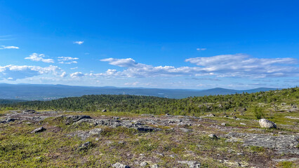 Expansive mountain view from the Kola Peninsula. Rocky tundra terrain stretches to the horizon under a vivid Arctic sky. A glimpse into the remote Russian north.