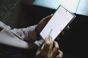 A person using a stylus on a smartphone with a blank white screen, ideal for showcasing note-taking, drawing, or e-signature applications.