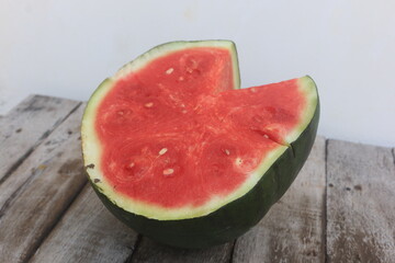 A piece of watermelon cut in half, the surface of the flesh has begun to oxidize, as can be seen...