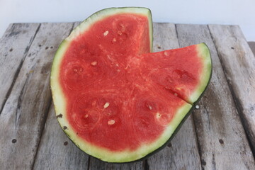 A piece of watermelon cut in half, the surface of the flesh has begun to oxidize, as can be seen from the pale red color.