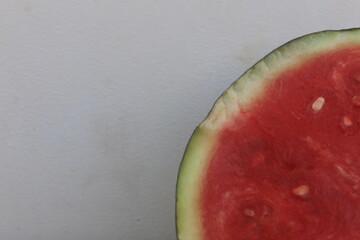 A piece of watermelon cut in half, the surface of the flesh has begun to oxidize, as can be seen...