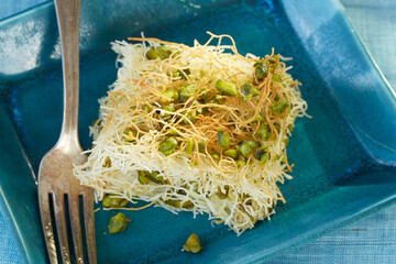 Close-up of a portion of traditional Middle Eastern konafa, made with shredded phyllo dough and...