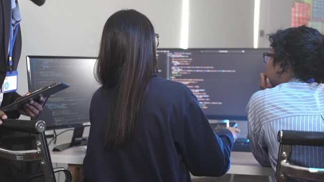 A senior software engineer leads a code review session, mentoring his diverse team on a complex project. Concept for agile development, knowledge transfer, and teamwork.