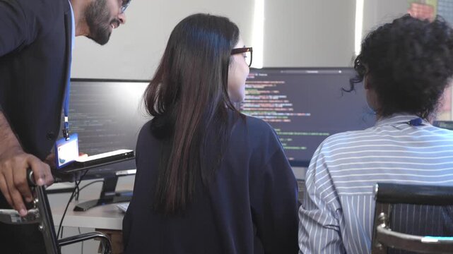 A senior software engineer leads a code review session, mentoring his diverse team on a complex project. Concept for agile development, knowledge transfer, and teamwork.