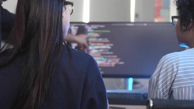 A senior software engineer leads a code review session, mentoring his diverse team on a complex project. Concept for agile development, knowledge transfer, and teamwork.