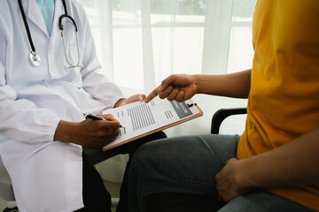 A male patient consults a doctor during a medical exam focused on prostate or testicular health,...