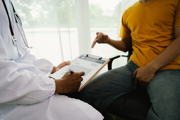 A male patient consults a doctor during a medical exam focused on prostate or testicular health,...