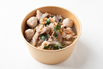 Thai noodles soup with sliced pork, minced pork, meatball and liver in a kraft paper bowl on white background, Traditional Thai street food