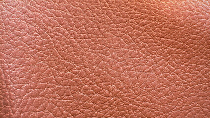Fototapeta premium Textured leather fills the frame. Surface is rough, shiny, and pink. Good for design, backgrounds, marketing, banners, and editorial use.