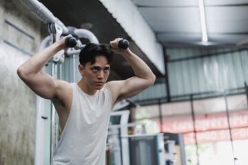 Determined asian athlete lifting weights in gym focus and strength training
