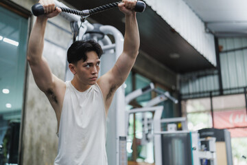Determined asian athlete lifting weights at the gym
