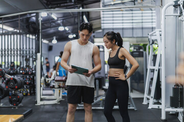 Personal trainer showing workout plan to sportswoman in gym