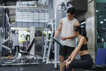 Personal trainer showing workout plan to sportswoman in gym