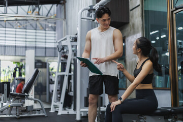 Personal trainer showing training plan to sportswoman in gym