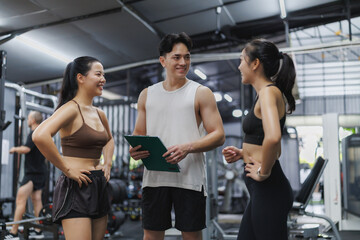 Personal trainer discussing workout routine with clients in gym