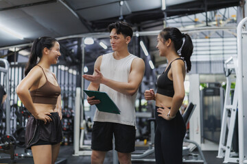 Personal trainer explaining training program to two women in gym