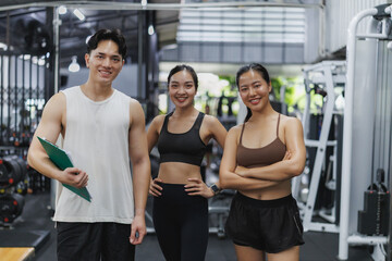 Personal trainer holding clipboard with two women in fitness center