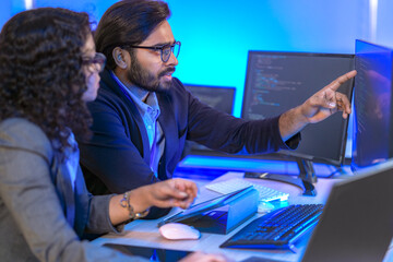 A data science team collaborates, analyzing a neural network model and code on multiple screens....