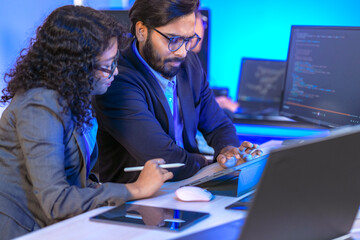 A data science team collaborates, analyzing a neural network model and code on multiple screens....