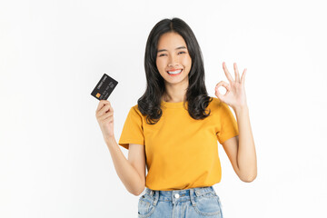 Smiling asian woman holding credit card and shows ok sign on white background.