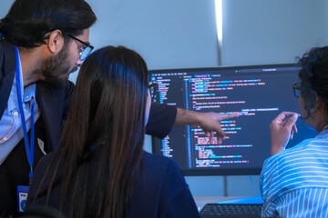 A senior software engineer leads a code review session, mentoring his diverse team on a complex...