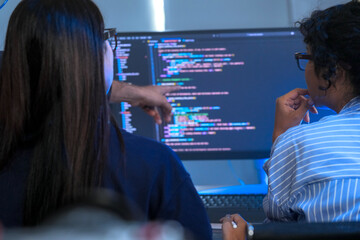 A senior software engineer leads a code review session, mentoring his diverse team on a complex...