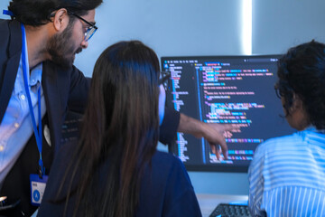 A senior software engineer leads a code review session, mentoring his diverse team on a complex...