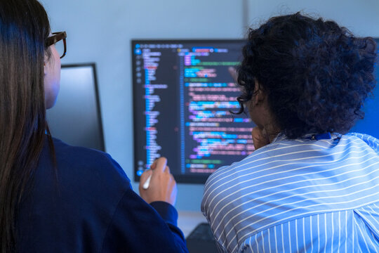 A senior software engineer leads a code review session, mentoring his diverse team on a complex project. Concept for agile development, knowledge transfer, and teamwork.