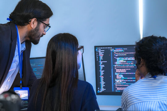 A senior software engineer leads a code review session, mentoring his diverse team on a complex project. Concept for agile development, knowledge transfer, and teamwork.