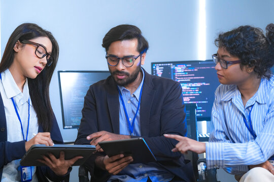 Diverse team of software engineers and data scientists collaborating on a project, using tablets and analyzing code. Concept for AI development, cybersecurity, and tech innovation. - Powered by Adobe