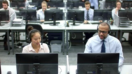 Diverse customer service agents with headsets work diligently in a busy, modern call center office. - Powered by Adobe