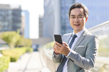 Mature businessman holding smart phone