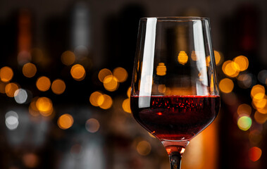 A glass filled with rich red wine sits elegantly, surrounded by soft golden lights in a warm and inviting atmosphere.