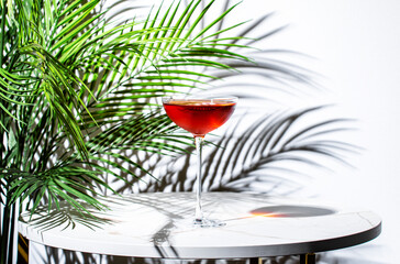 red cocktail with whiskey, port wine, and amaro served on a stylish table with palm shadows