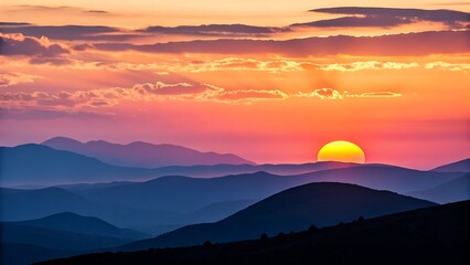 Fototapeta premium Vibrant sunset over layered blue mountains with fiery sky
