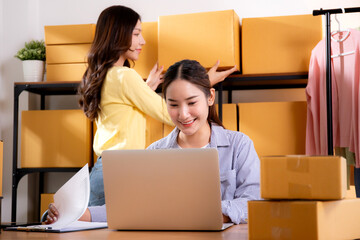 Two young asian businesswoman checking order of customer for laptop computer and document, shipment...