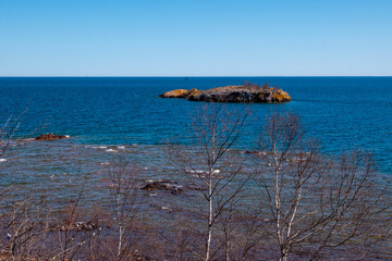 Small island of the North Shore of beautiful Lake Superior in Minnesota, with blue sky and water,...