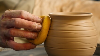 Close up master man craftsman carefully rubbing clay bowl jug vase artisan using holding wet yellow...