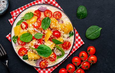 vegan salad with couscous, cherry tomatoes, red onion, fresh baby spinach and juicy orange, top view