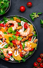 seafood salad with shrimp, mussels, squid, oranges, tomatoes, green lettuce and olemon dressing, top view